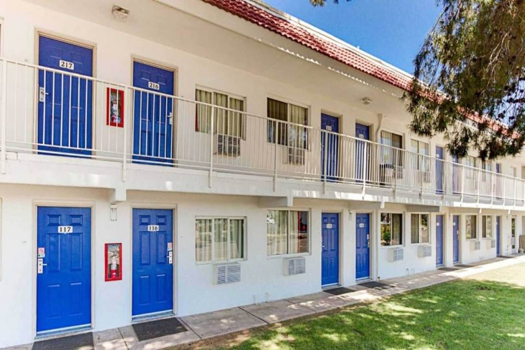 A multi-story motel with blue doors and white railings.