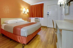 Ein Hotelzimmer mit einem Bett, einem Schreibtisch, einem Stuhl, einer Klimaanlage und einer Tür.