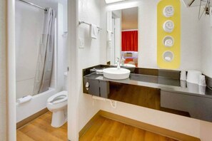 Ein modernes Badezimmer mit Badewanne, Toilette und Waschbecken mit Spiegel darüber.