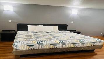 Ein Schlafzimmer mit einem Bett, Nachttischen und einer gemusterten Tagesdecke.