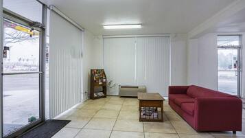 Ein Empfangsbereich mit einer roten Couch, einem Holztisch und einer Pinwand.
