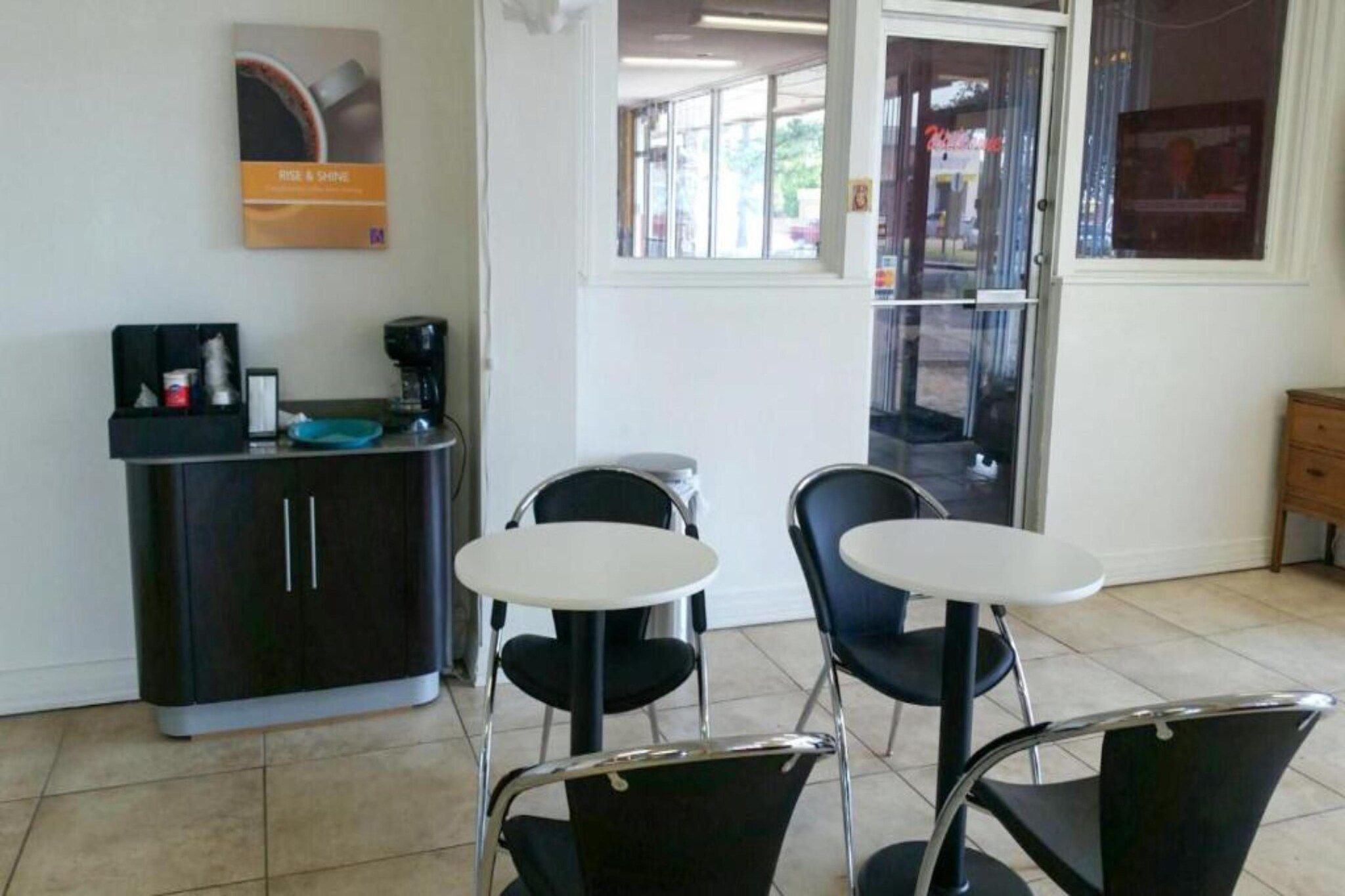 A small, clean room with a kitchenette, two chairs, a table, and a window with a view of the outside.