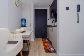 Une cuisine compacte équipée d’un distributeur d’eau, d’un téléphone et d’un four à micro-ondes.
