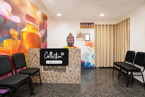 A reception area with a reception desk, chairs, a Buddha statue, and a wall with floral and geometric patterns. - Collection O Shriram Gateway Road (Chennai)