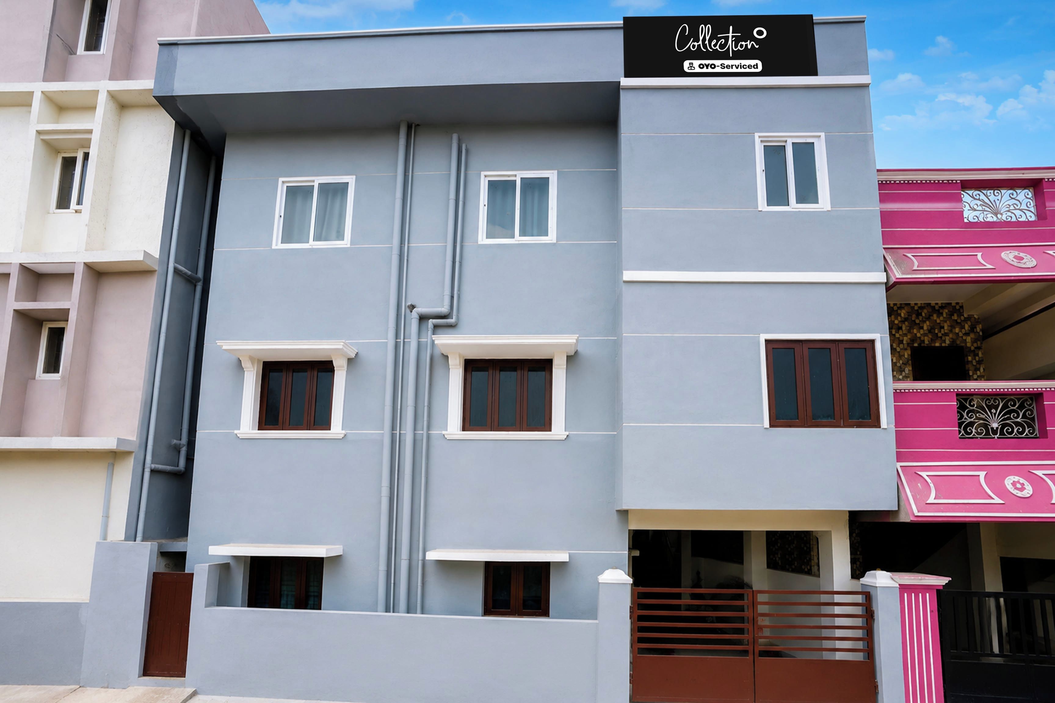 A multi-story building with a grey facade, white window frames, and a black sign indicating a service.