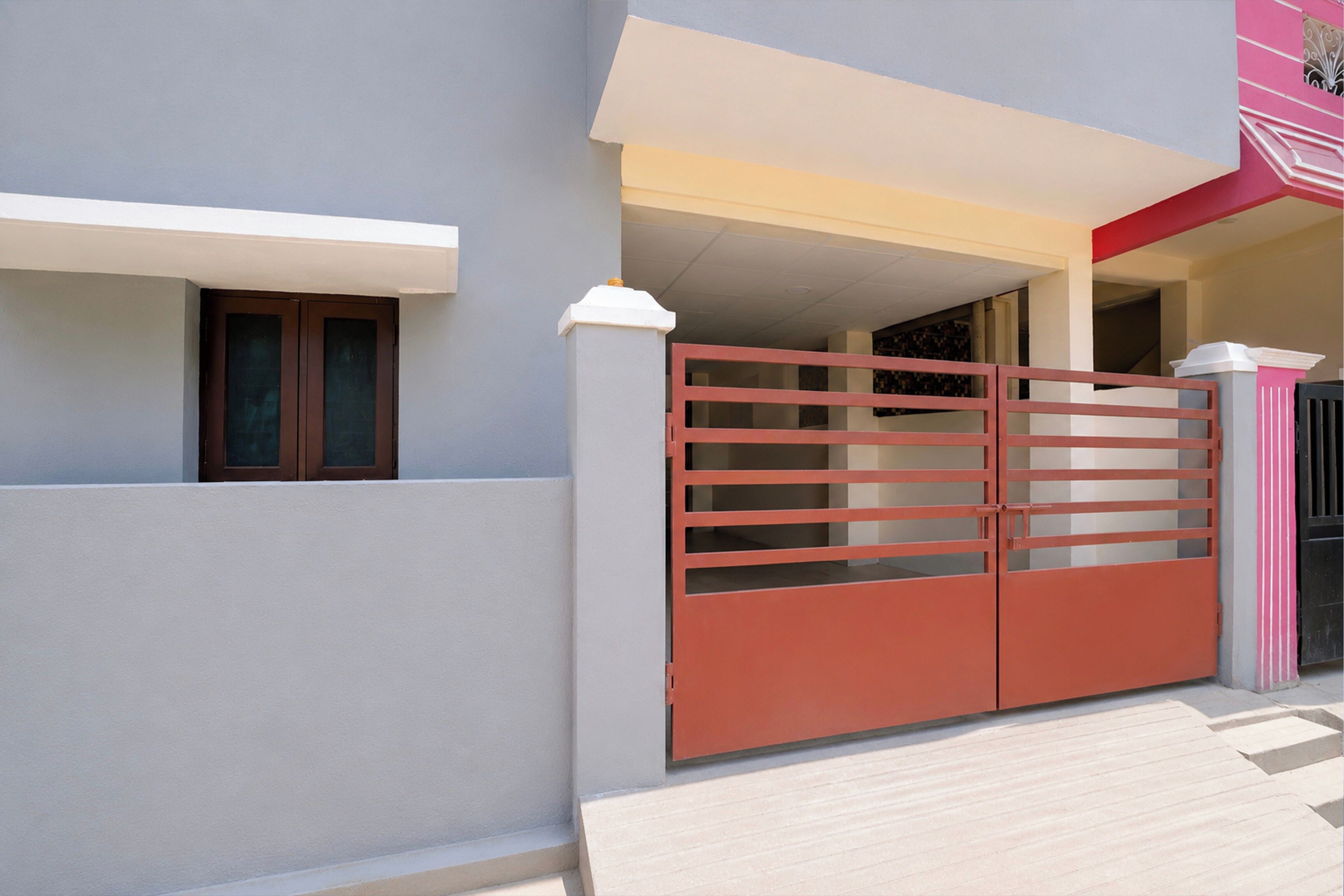 Uma casa moderna com portão fechado, janela visível e escadaria que leva ao andar superior.