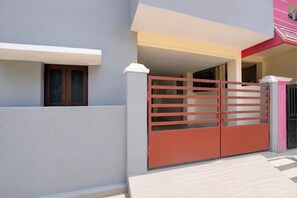 A modern house with a gated entrance, a visible window, and a staircase leading to the upper floor. - Collection O Shriram Gateway Road (Chennai)