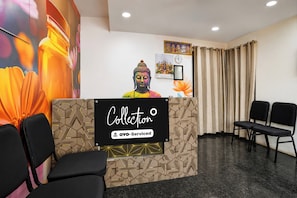 A reception desk with a geometric pattern, a Buddha statue, and a clock on the wall. - Collection O Shriram Gateway Road (Chennai)