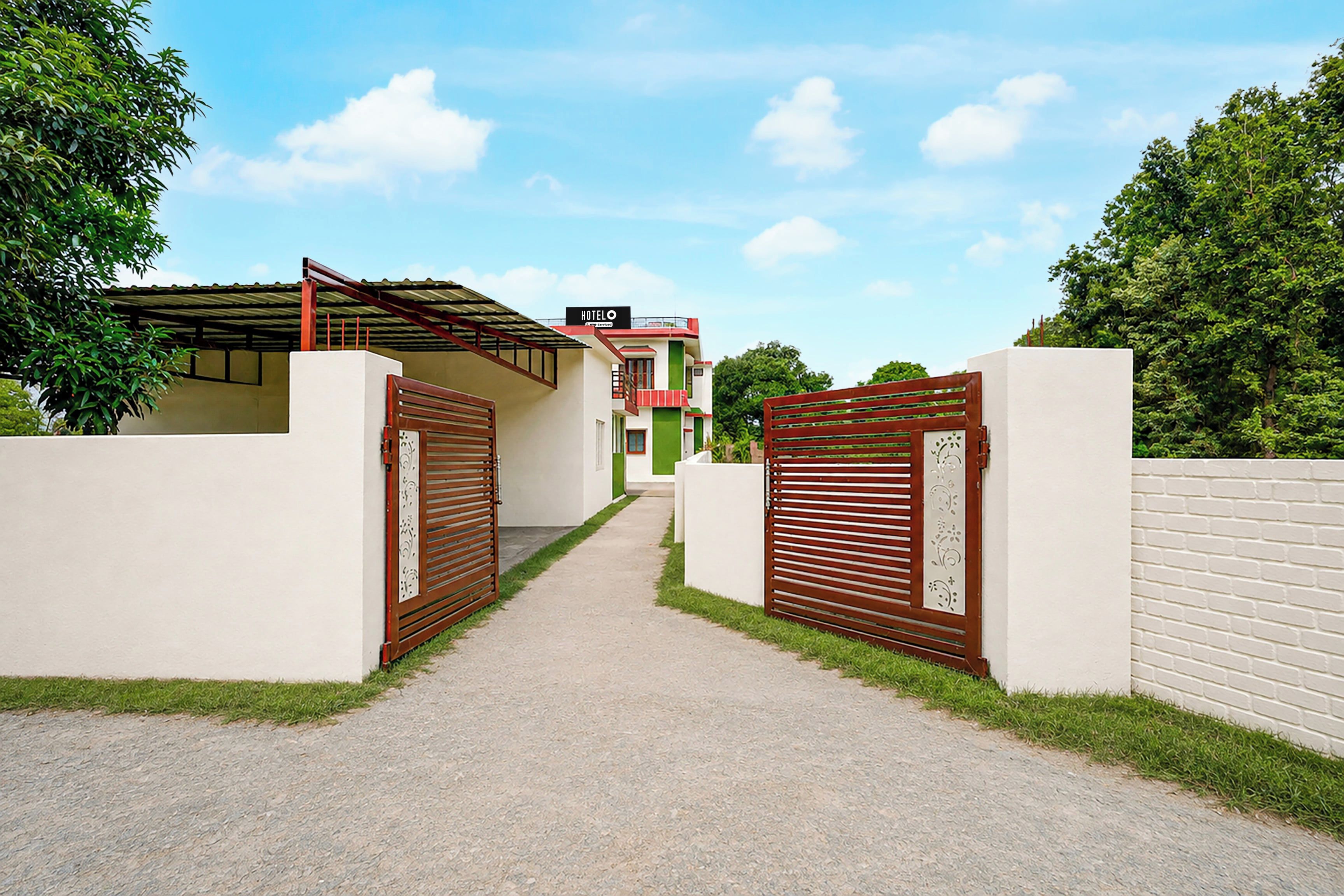 Uma entrada fechada por portão para um hotel, com um caminho bem definido que leva ao edifício.