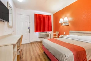 Une chambre d’hôtel équipée d’un lit, d’un bureau, d’une chaise et d’un téléviseur.