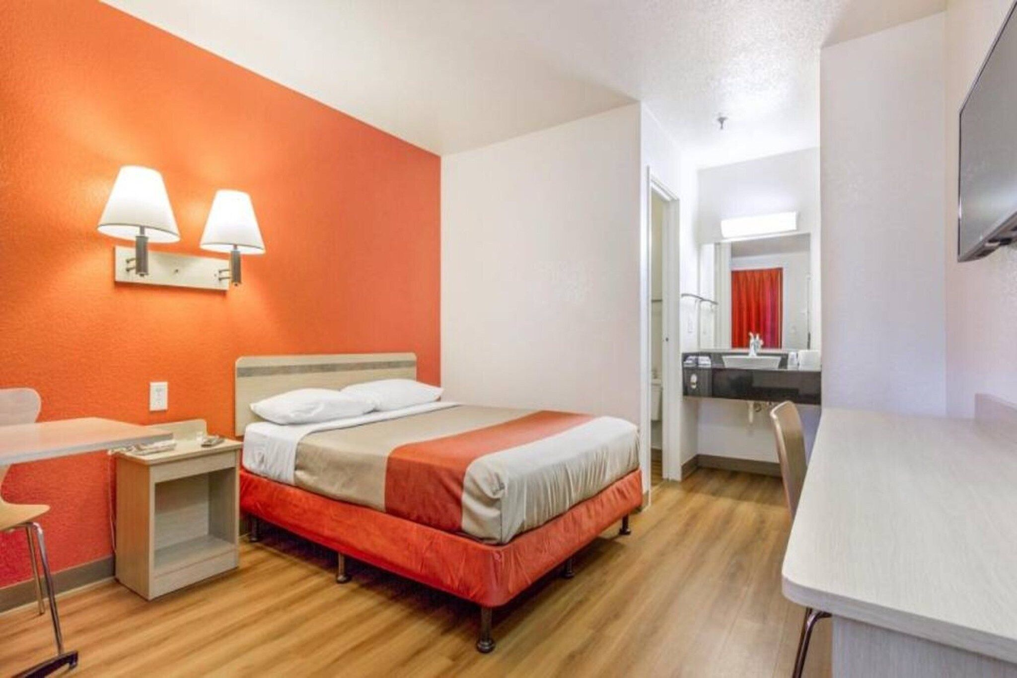 A hotel room with a bed, bedside tables, a desk, and a mirror.