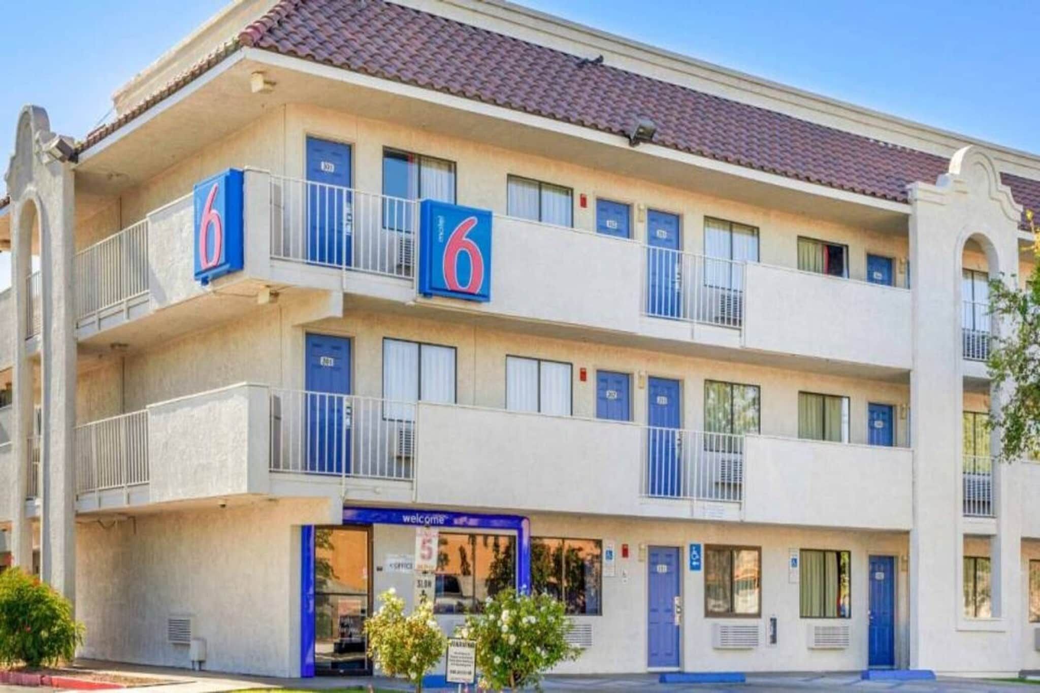 Een meerlaags hotel met balkons, een winkelpui en een heldere lucht.