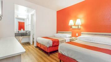A hotel room with two beds, a desk, and a bathroom.