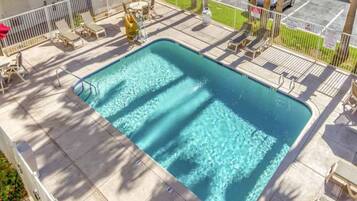 A rectangular swimming pool with a tiled deck surrounding it.