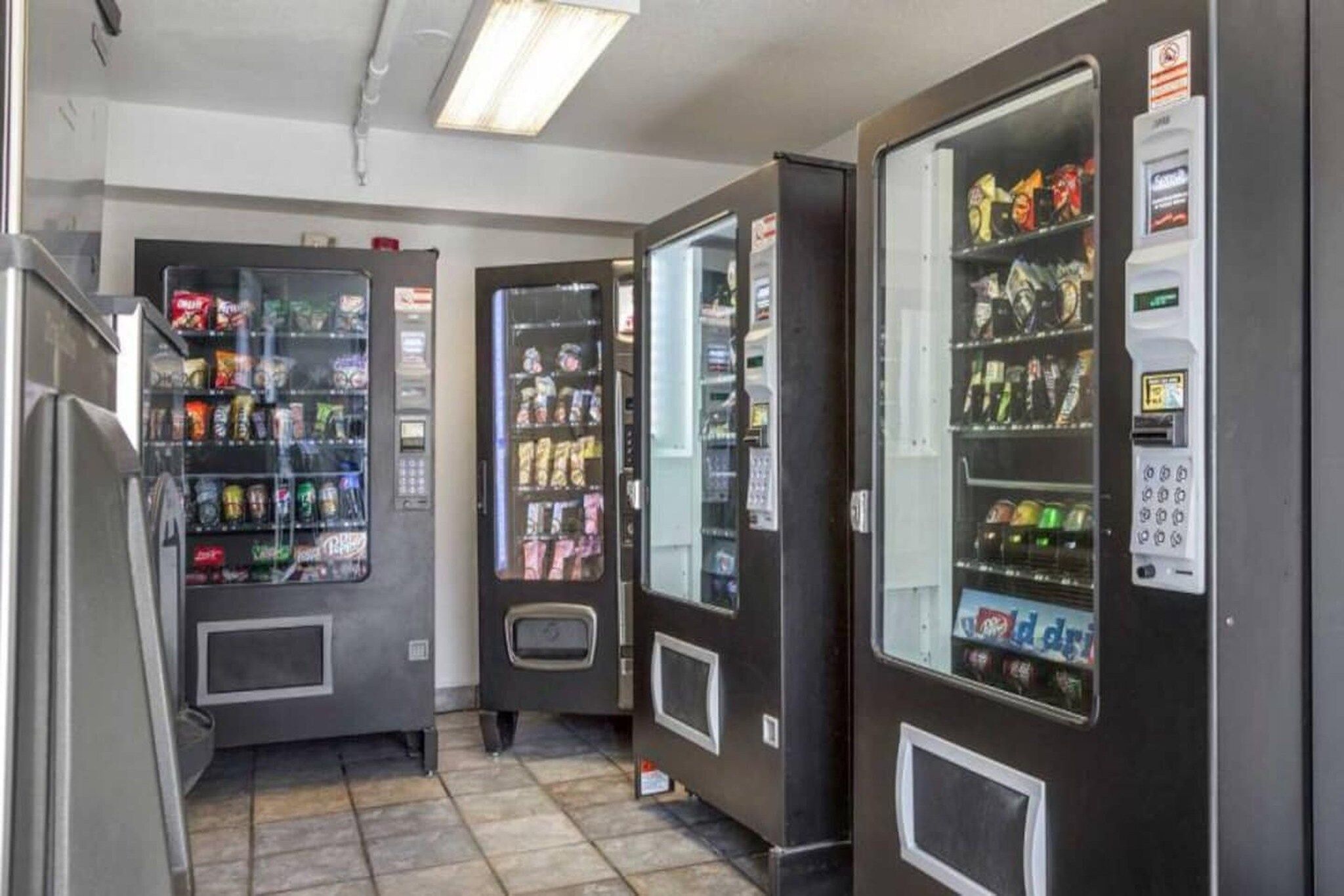 A row of vending machines with various snacks and drinks, and a payment terminal on the right.
