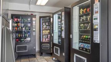 A row of vending machines with various snacks and drinks, and a payment terminal on the right.