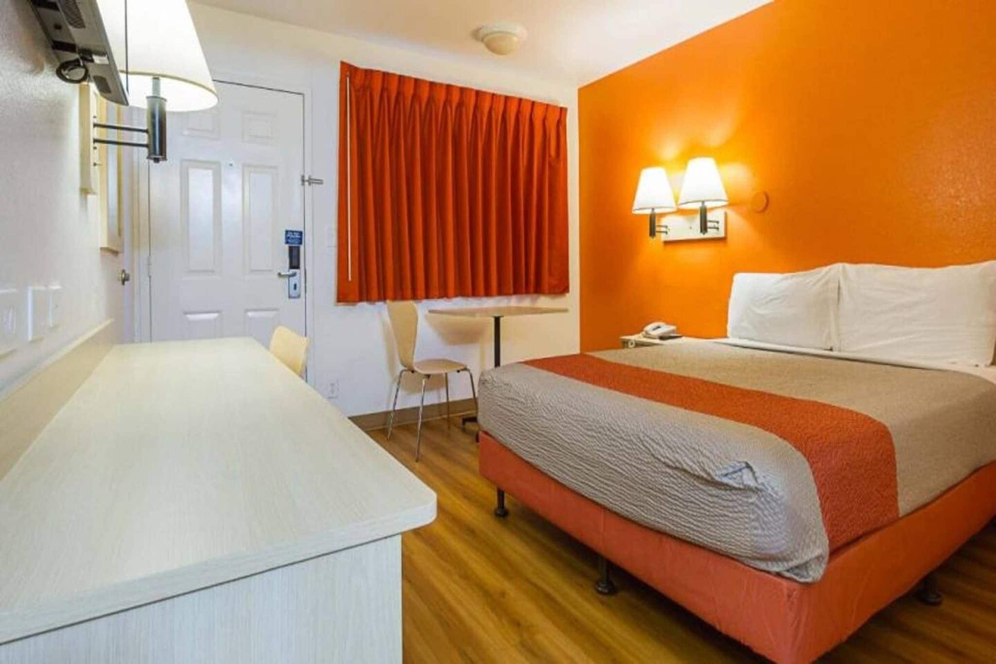 A hotel room with a bed, a desk, and a chair.