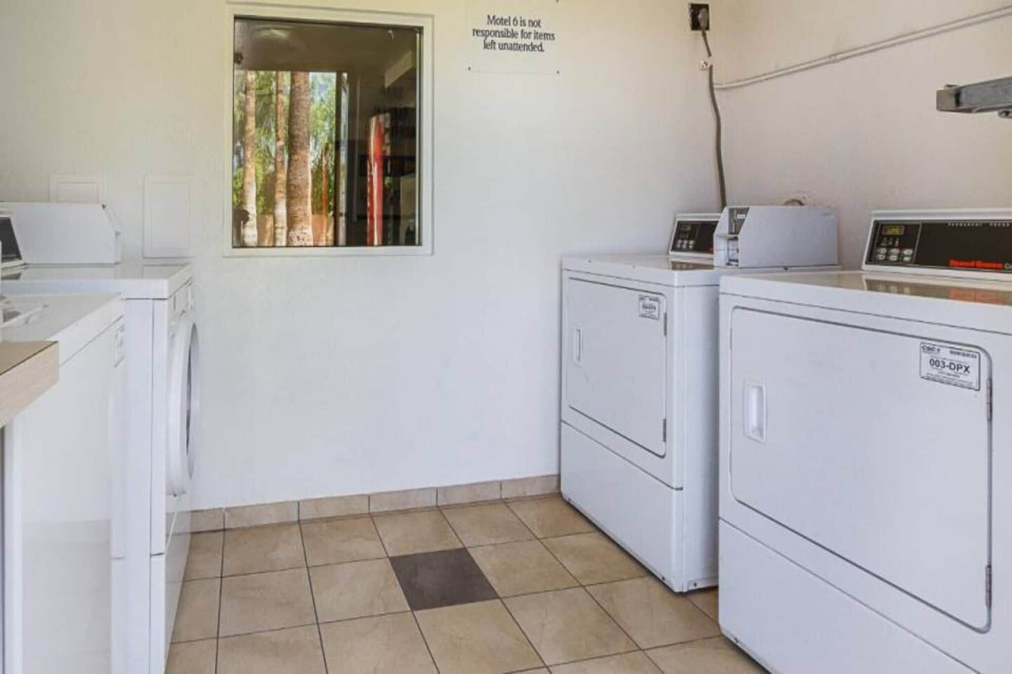 A laundry room with two washing machines, a dryer, and a sign stating 'Motel is not responsible for items left unattended.'