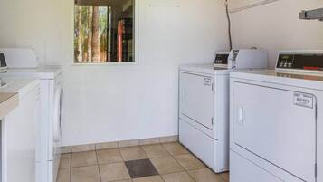 A laundry room with two washing machines, a dryer, and a sign stating 'Motel is not responsible for items left unattended.'