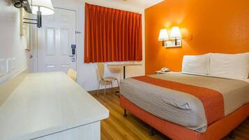 A hotel room with a bed, a desk, and a chair.
