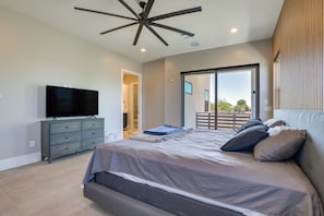 A modern bedroom with a large bed, a flat-screen TV, a ceiling fan, and a sliding glass door leading to a balcony. - 1 Mi to South Mtn Park! Home w/ Poolside Oasis (Phoenix)