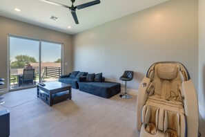 A modern living room with a sofa, a massage chair, and a dining area with a table and chairs. - 1 Mi to South Mtn Park! Home w/ Poolside Oasis (Phoenix)