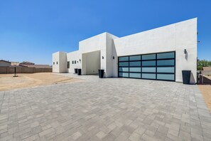 En moderne bygning med stor garageport, asfalteret indkørsel og en klar blå himmel.