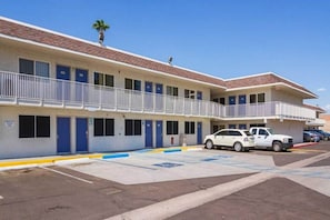 Ein Motel mit einer zweistöckigen Struktur, einem Parkplatz und einem weißen Auto vor der Fassade.