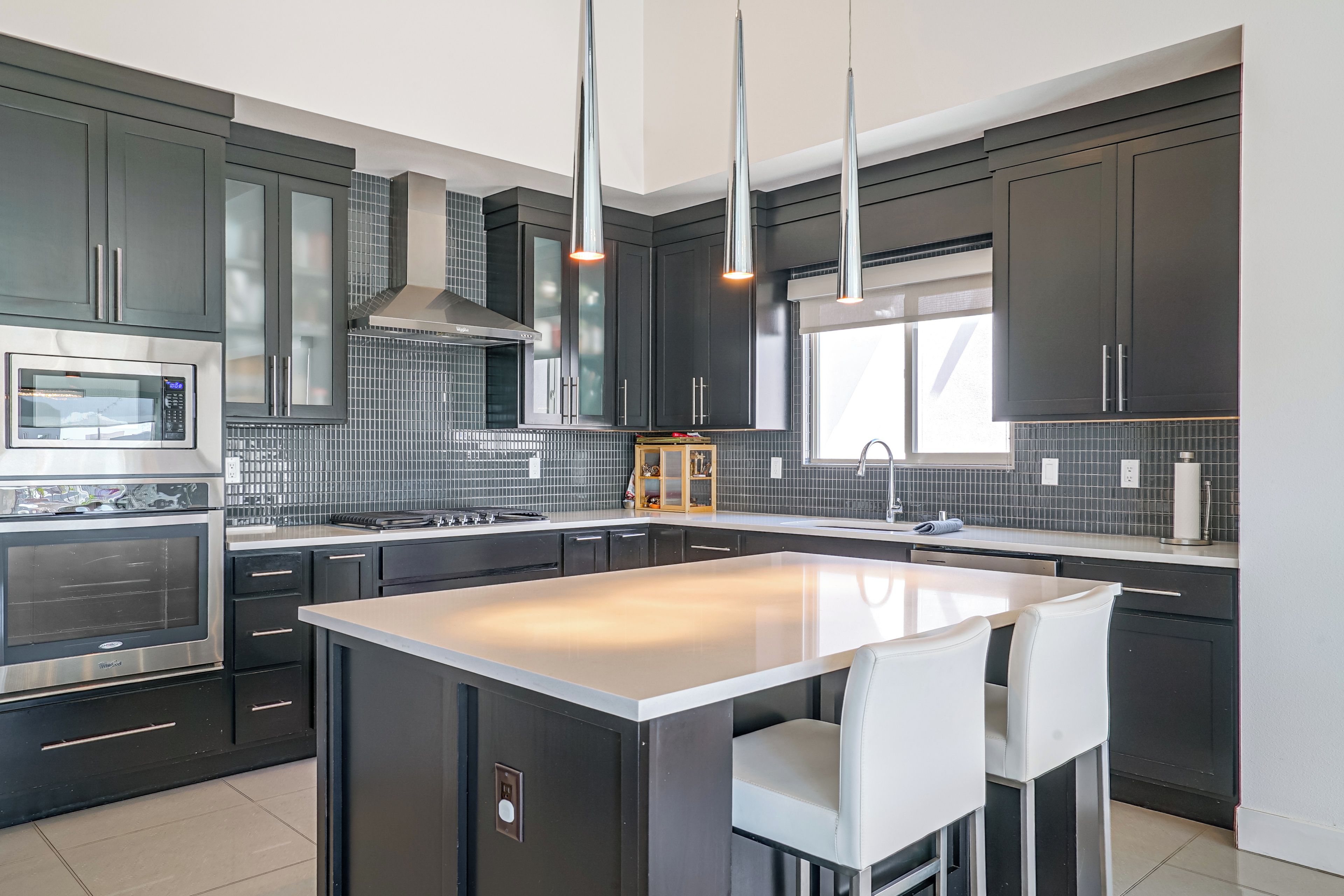 A modern kitchen with a central island, stainless steel appliances, and pendant lighting.