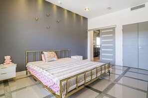 Ein modernes Schlafzimmer mit einem großen Bett, Nachttischen, einem Kleiderschrank und einem durch eine offene Tür einsehbaren Badezimmer.