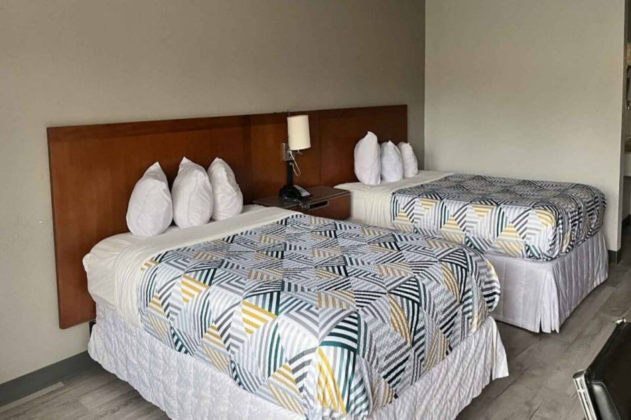 Una habitación de hotel con dos camas, cada una con una colcha estampada y almohadas blancas.