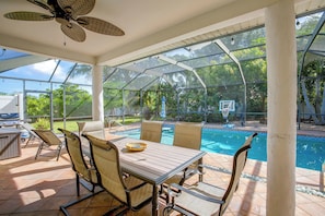 Un espacio al aire libre cubierto con piscina, sillas y una mesa.