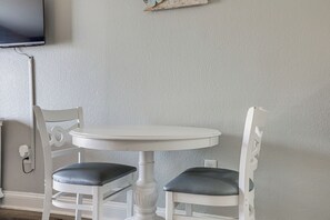 A white round table with two chairs, each with a cushioned seat. - Beachfront Bliss & Ocean Views: Myrtle Beach Gem (Myrtle Beach)