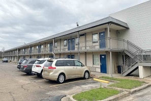 A motel with a parking lot and a building with multiple balconies.