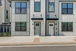 Un immeuble résidentiel moderne à plusieurs étages, doté d’une façade symétrique, de grandes fenêtres et d’une entrée centrale.