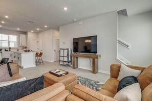 Un salon moderne avec un canapé, une table basse et un téléviseur fixé sur un meuble en bois.