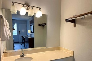 A bathroom with a sink, mirror, and overhead lighting. - 1 King Bed | Non-Smoking (Forrest City)