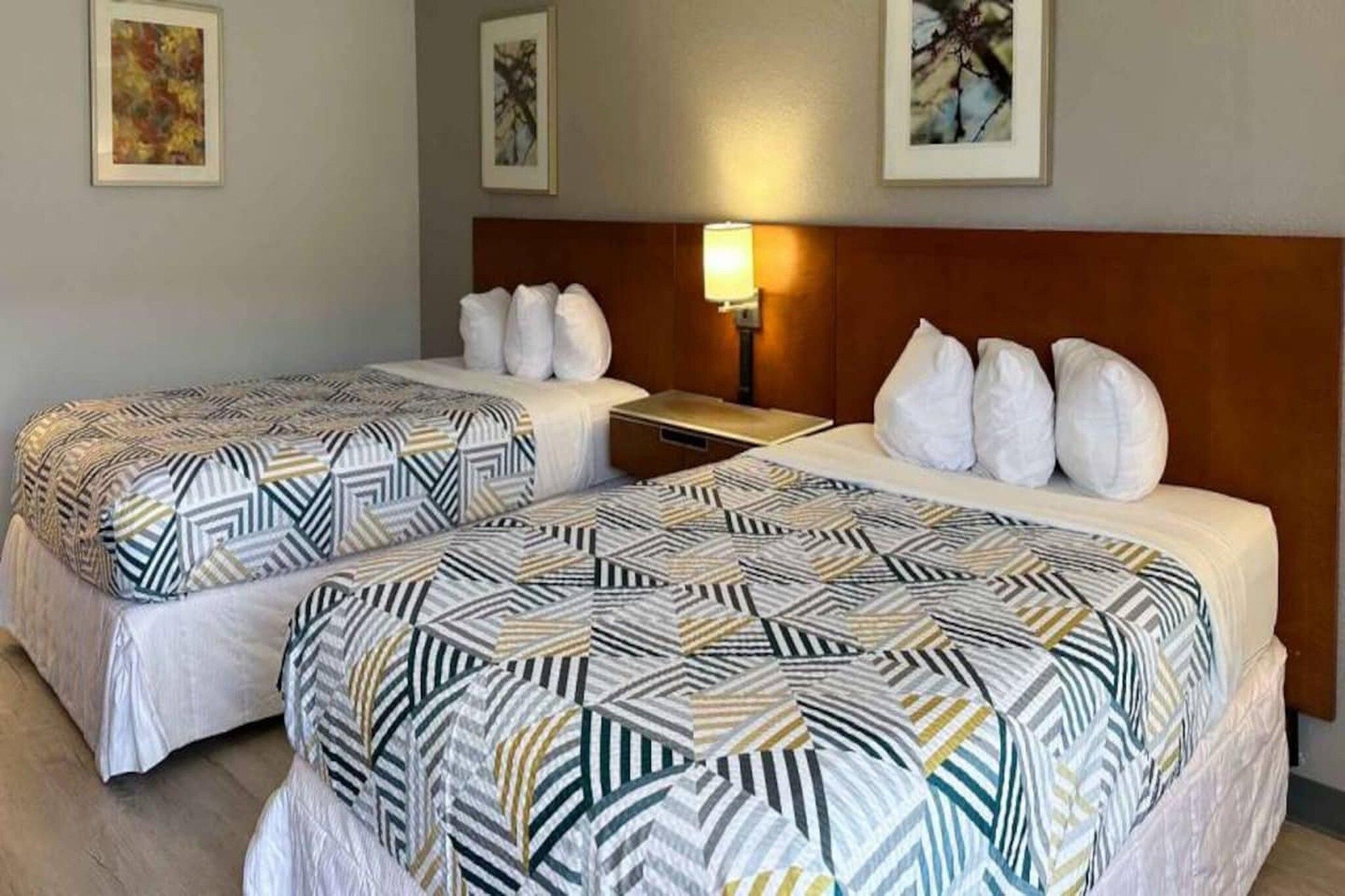 Une chambre d’hôtel avec deux lits, chacun doté d’une literie à motifs, d’une tête de lit en bois et d’une lampe de chevet.