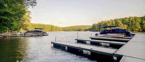 A calm lake with docked boats and a dock extending into the water.