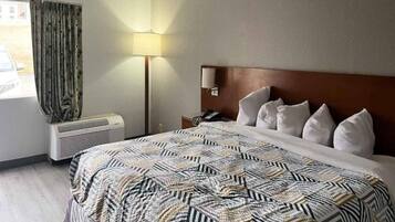 Habitación de hotel con cama, lámpara de noche, teléfono y ventana con cortinas.