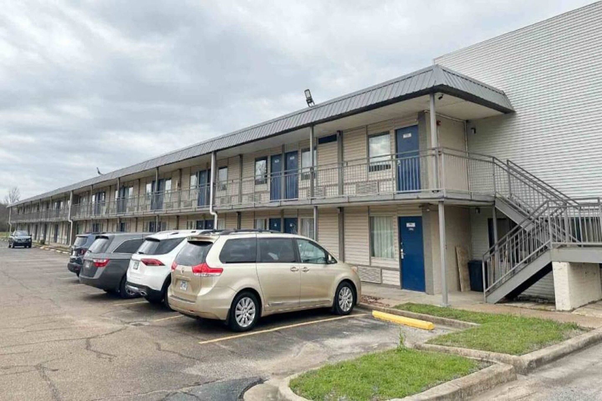 A motel with a parking lot and a building with multiple balconies.