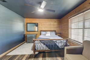 Un dormitorio con cama, una silla, una mesita de noche, un espejo y una ventana con persianas.