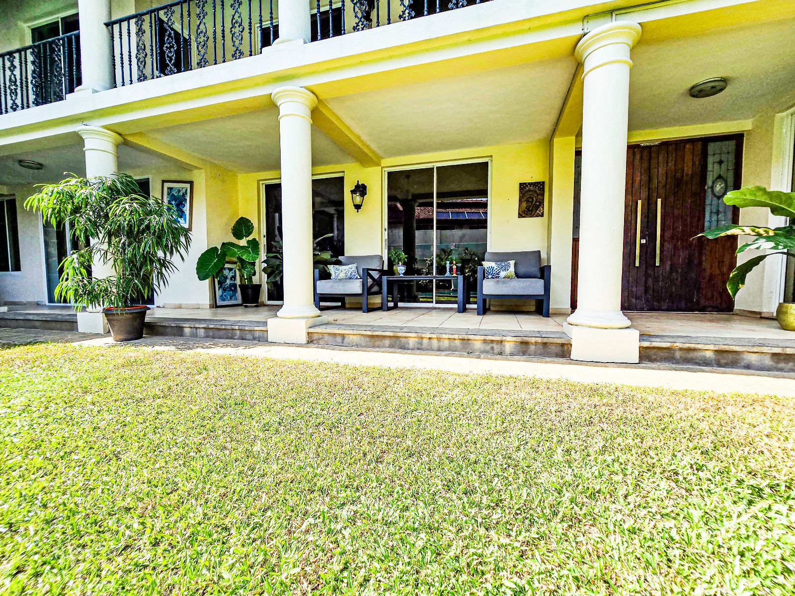 A building with a covered porch, columns, and outdoor seating.