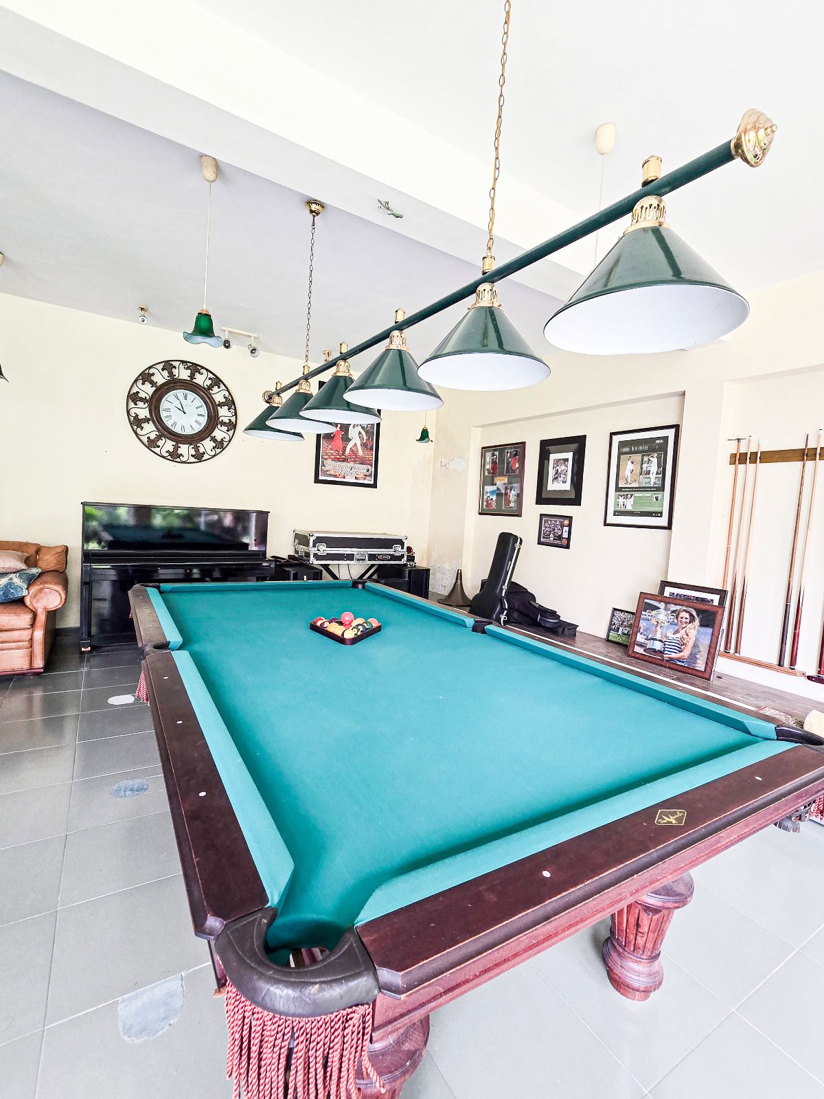 A pool table with a green felt surface, surrounded by a pool table skirt, and a pool cue rack to the right.
