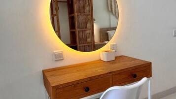 A desk with a round mirror, a white chair, and a wooden cabinet.