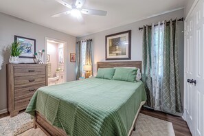 A bedroom with a bed, dresser, ceiling fan, and a door with curtains. - Raleigh Townhome w/ Deck: Near Shops & Dining (Raleigh)