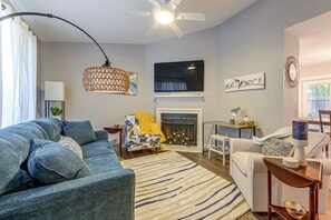 A living room with a sofa, a chair, a fireplace, a television, and a ceiling fan. - Raleigh Townhome w/ Deck: Near Shops & Dining (Raleigh)