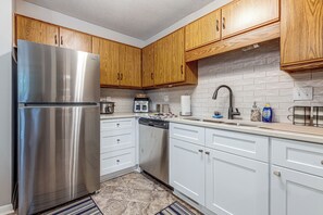 A kitchen with wooden cabinets, stainless steel appliances, and a tiled backsplash. - Raleigh Townhome w/ Deck: Near Shops & Dining (Raleigh)
