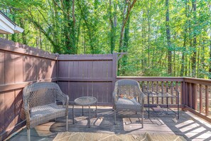 An outdoor patio with wicker furniture, a wooden deck, and a view of a forested area. - Raleigh Townhome w/ Deck: Near Shops & Dining (Raleigh)