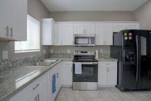 A kitchen with white cabinets, a stainless steel refrigerator, a microwave, an oven, and a sink. - Townhome 1 Mi to Midtown & Botanical Gardens! (Tucson)